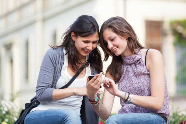 Two women looking at mobile phone smiling