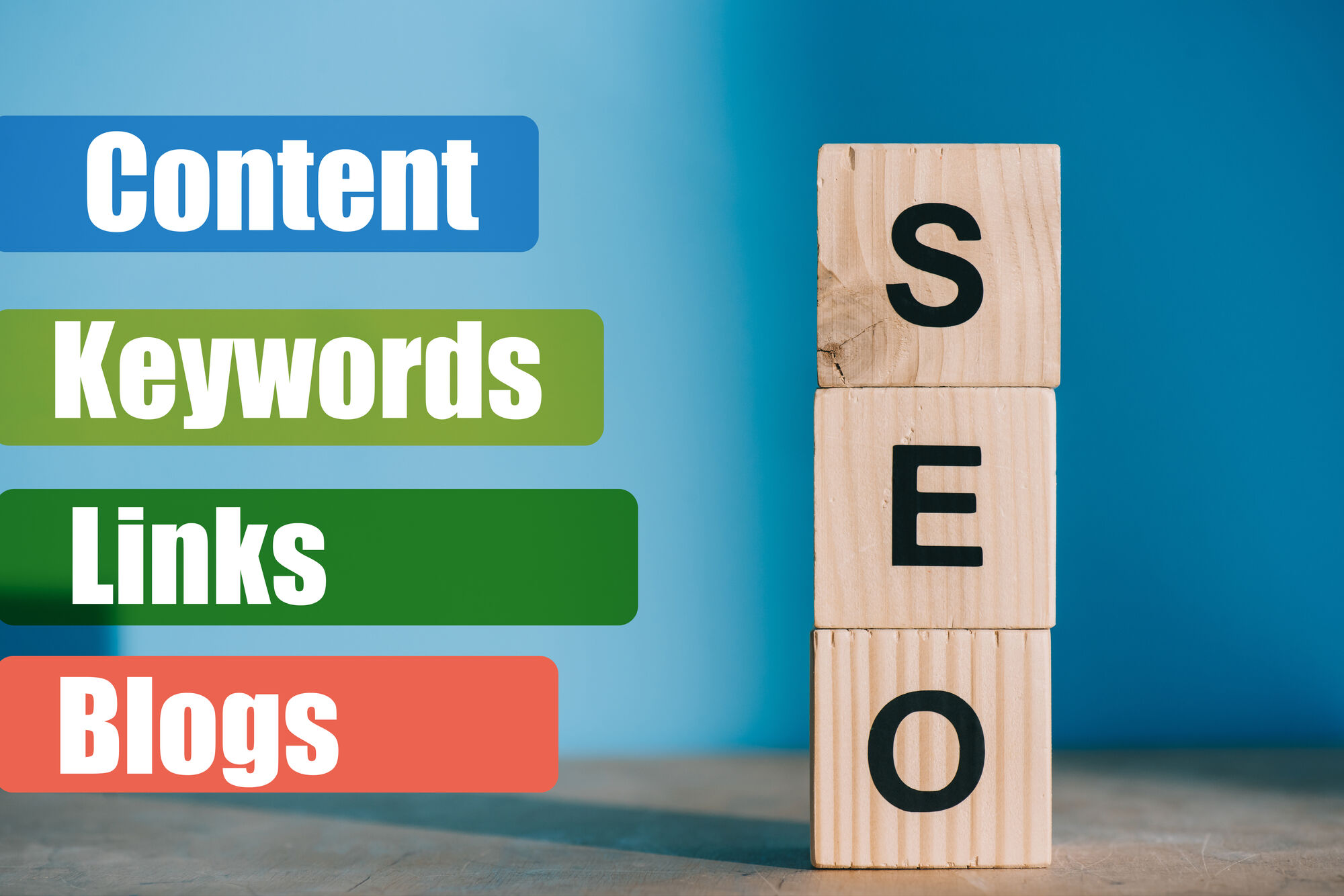 SEO spelled using wooden blocks next to content, keywords, links and blogs signs