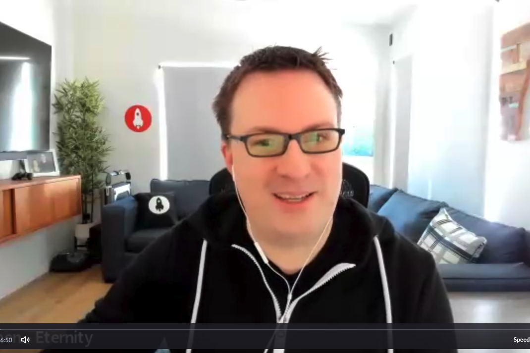 Smiling man in glasses and a black hoodie on a video call in a bright, modern living room