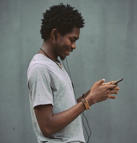 A photograph of a person in profile as they interact with their mobile phone