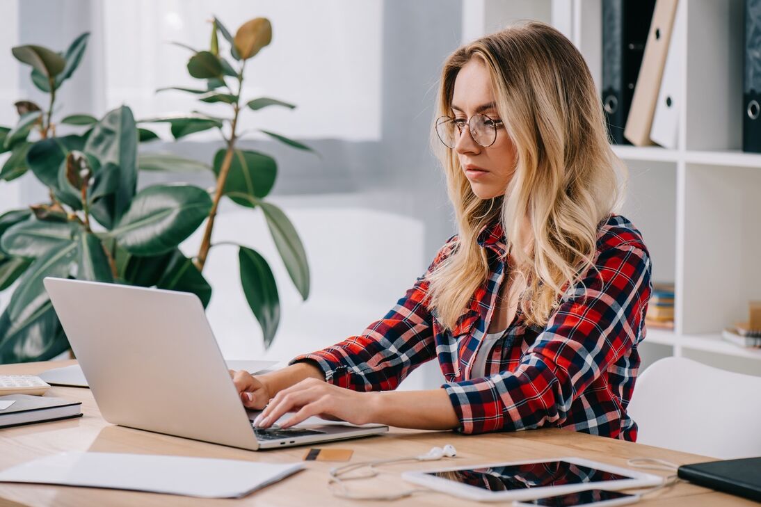 Young lady with glasses and flannel shirt using a laptop