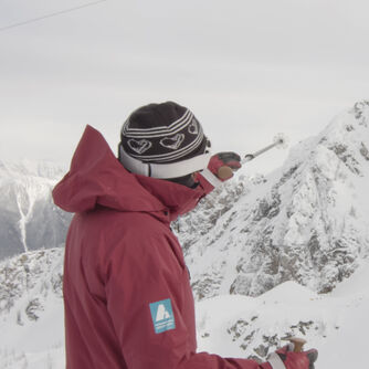 Advanturer - a man in an advanturer coat pointing at a mountain peak