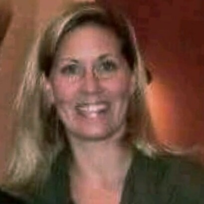 Smiling woman with long blonde hair, wearing a green shirt.