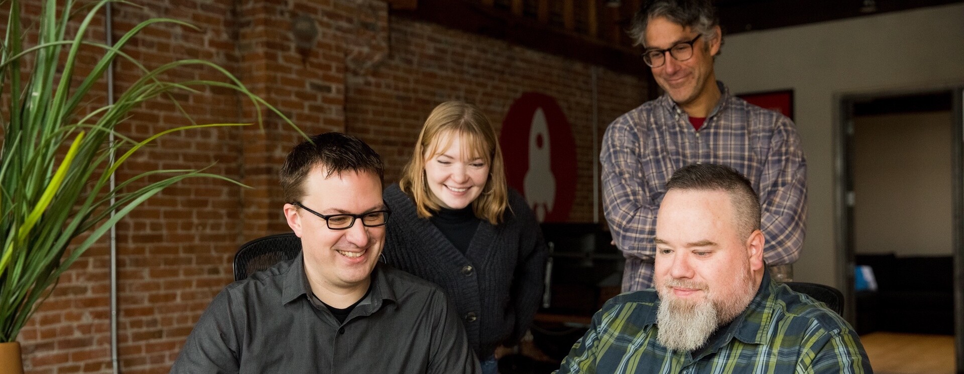 Four members of the Eternity team gathered around a computer, smiling and engaged in discussion.