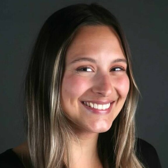 Smiling woman with long, dark hair against a dark background.