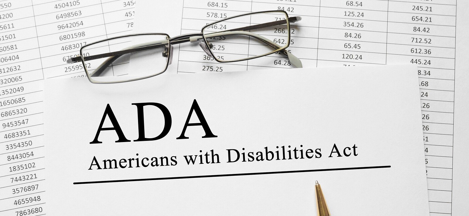 Document titled "ADA Americans with Disabilities Act" beside glasses and financial data.