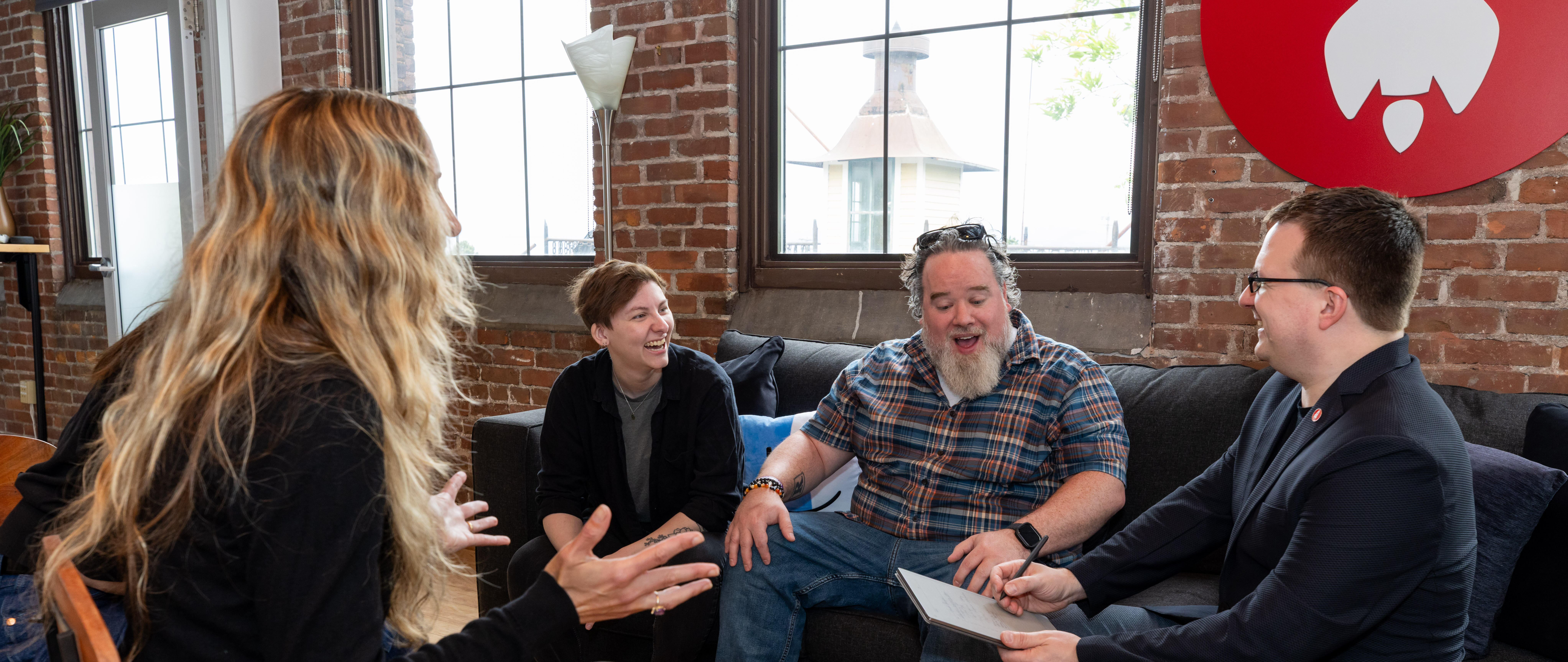 Four members of the Eternity crew engaged in lively discussion in a cozy, brick-walled setting.