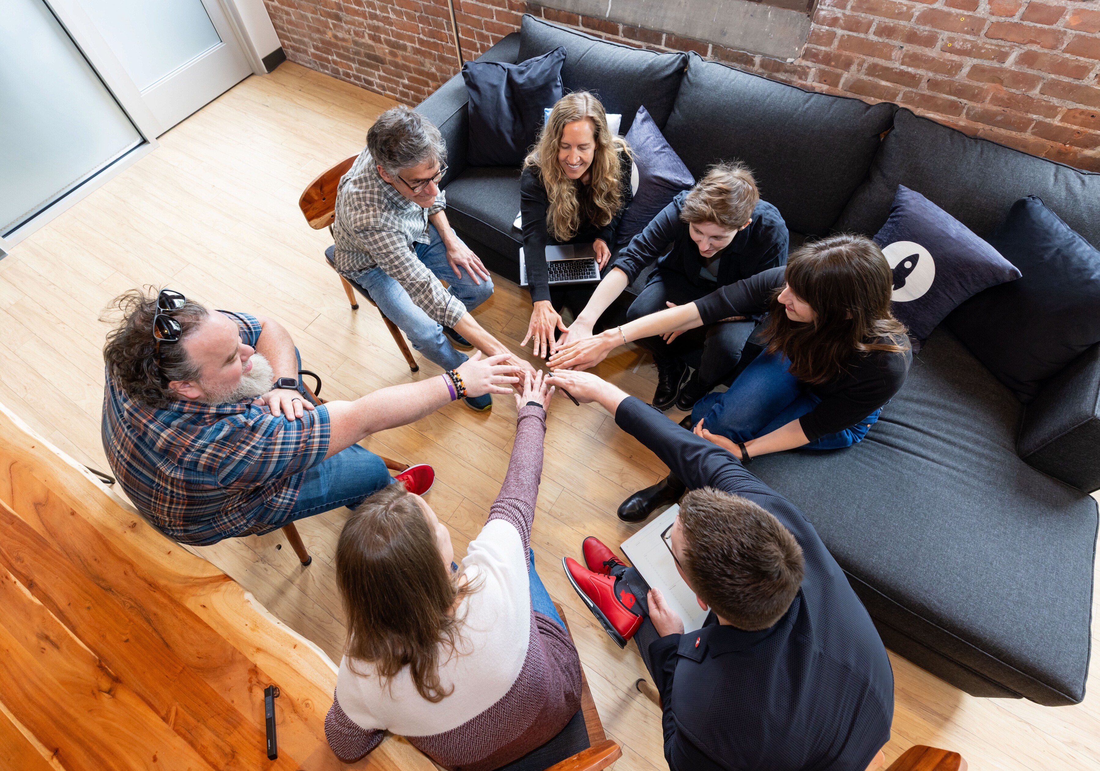 A group of people gathered in a circle, joining hands in a collaborative gesture.