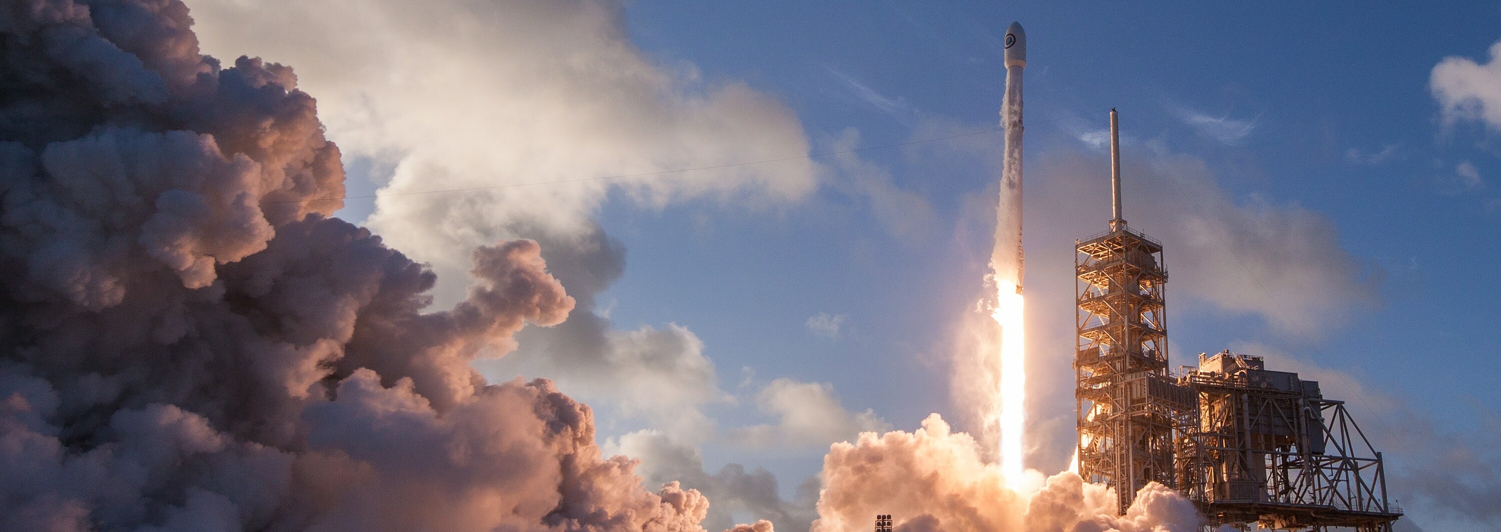 Rocket launching into the sky, surrounded by smoke and clouds.