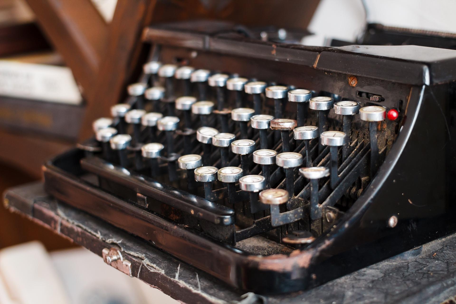 Vintage black typewriter with silver keys, slightly dusty and worn