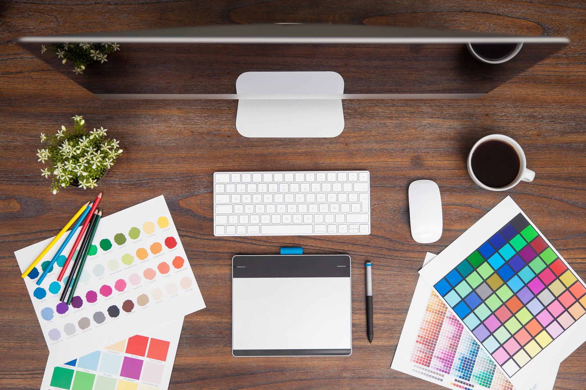 Desk setup with a computer, color swatches, pens, and a coffee cup