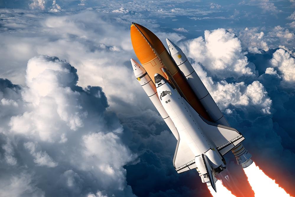 Space shuttle launching through clouds with fiery exhaust.