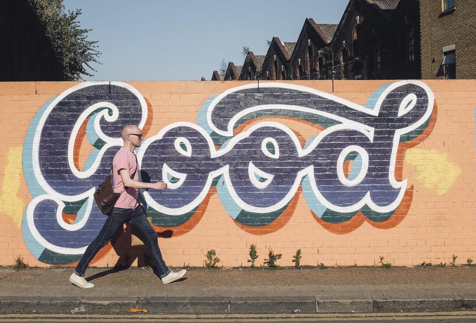 Person walking past a colorful mural that says 