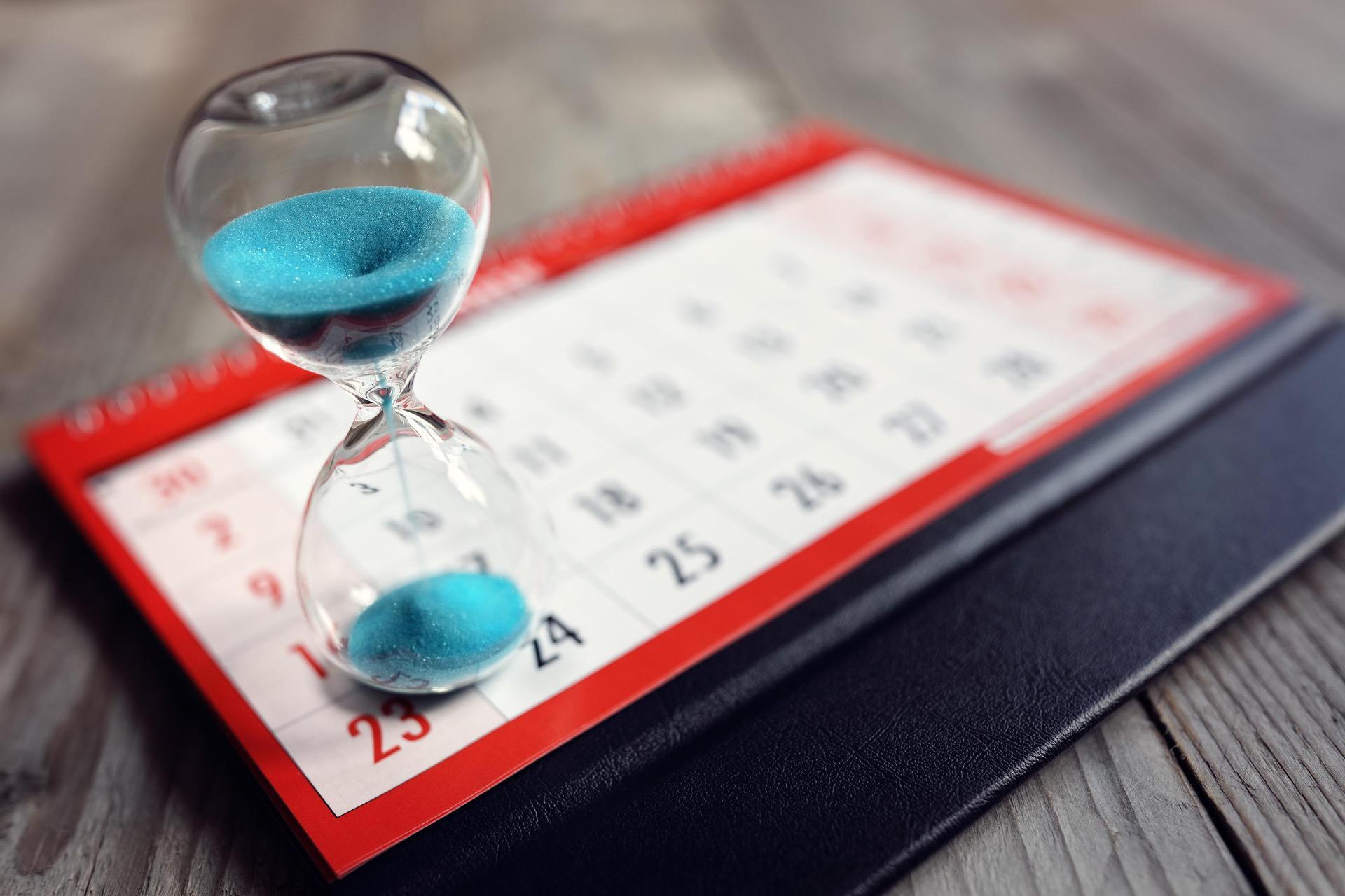 Hourglass with blue sand on a red calendar with highlighted dates