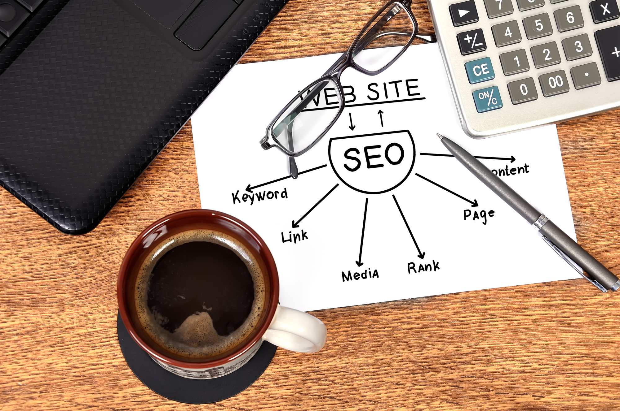 Top view of illustration showing SEO scheme on white paper with adjacent coffee mug, eyeglasses and pen