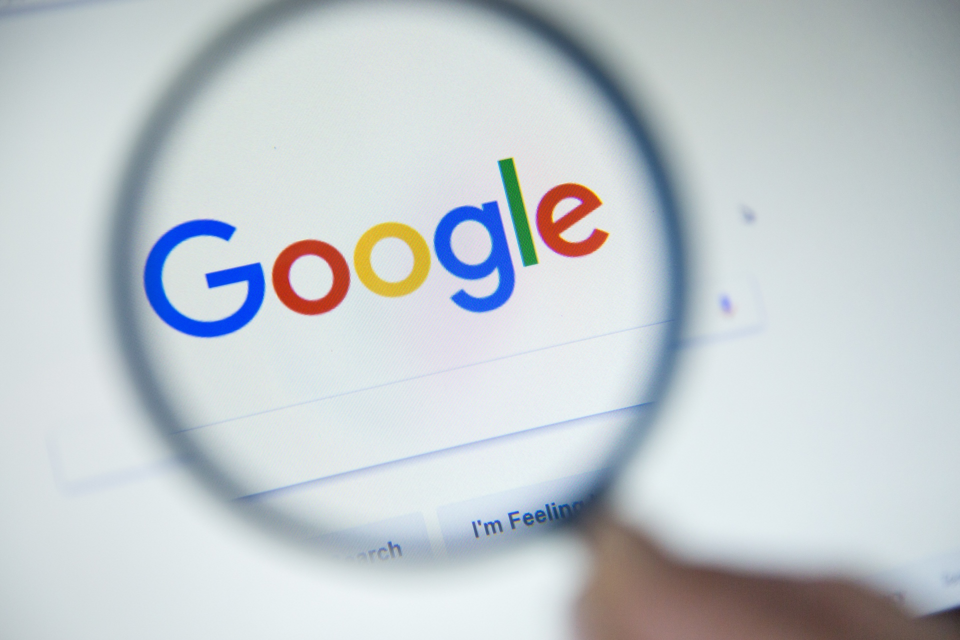 a blurry background with a magnifying glass circling the Google logo, with that part of the photo in focus