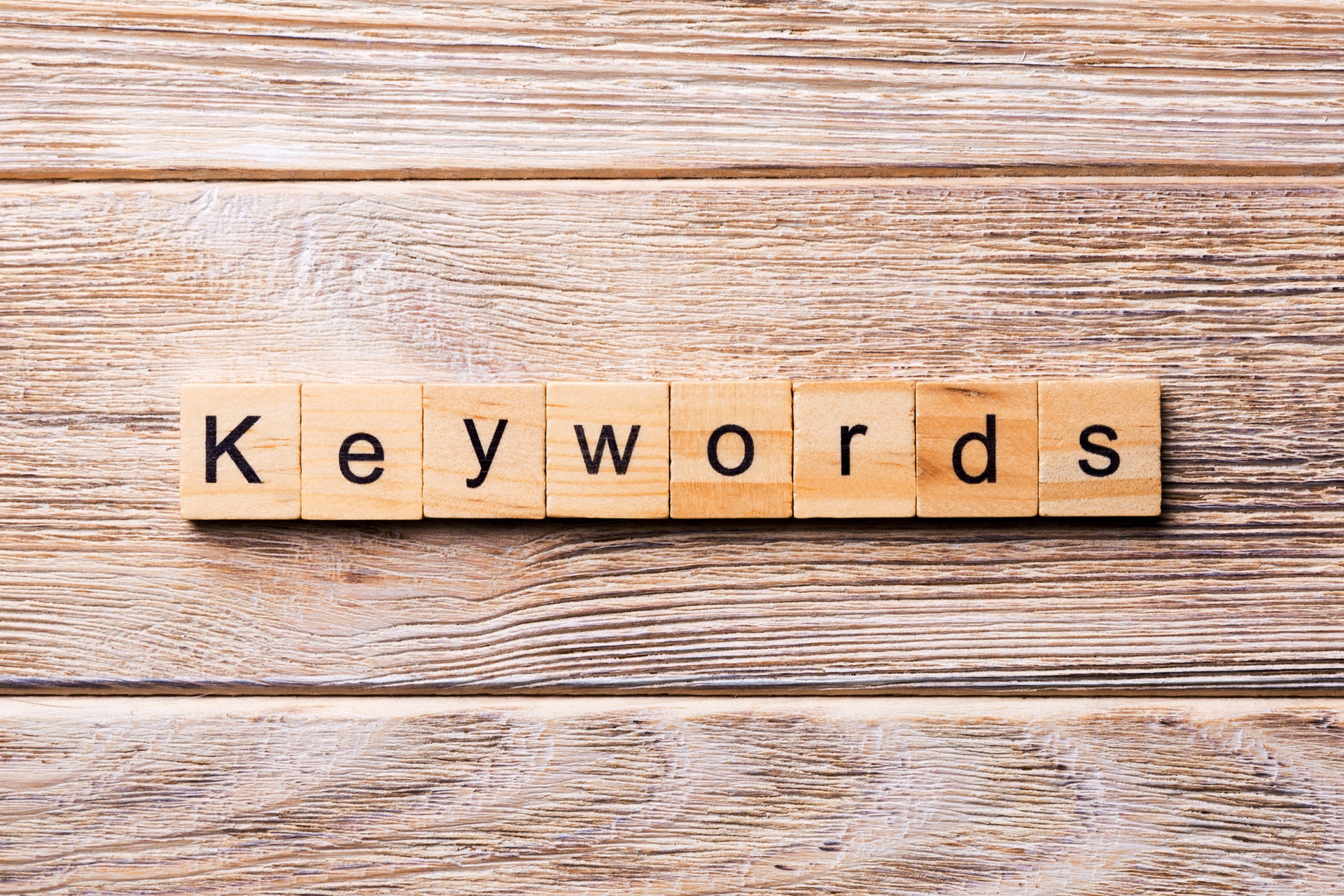wooden background with scrabble-style tiles spelling out the word keywords