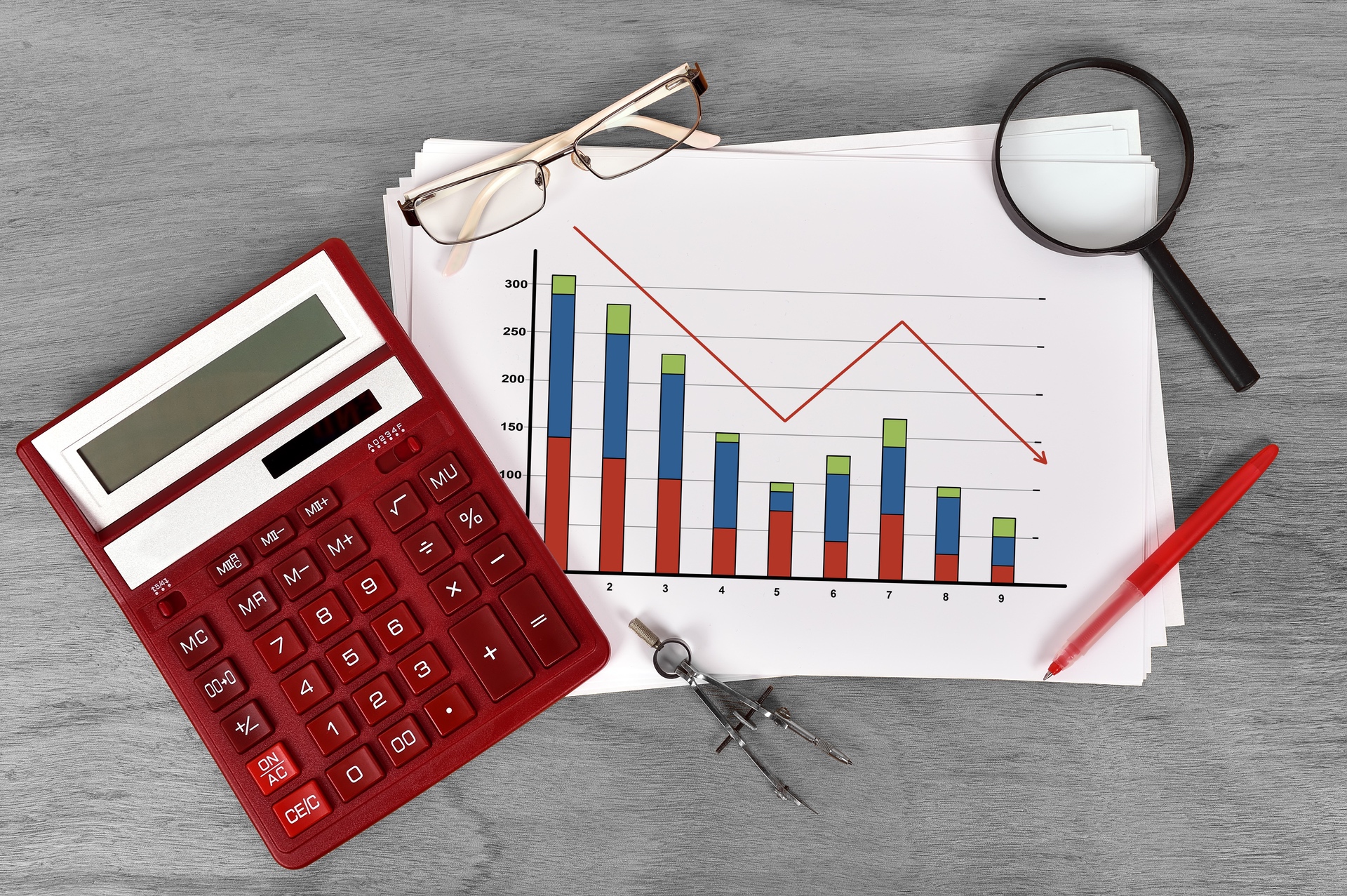 calculator, graph of downward motion, magnifying glass, pen and glasses