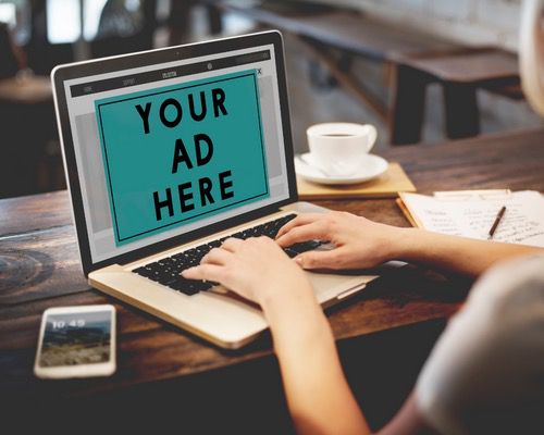 Person typing on a laptop displaying a mock advertisement on the screen