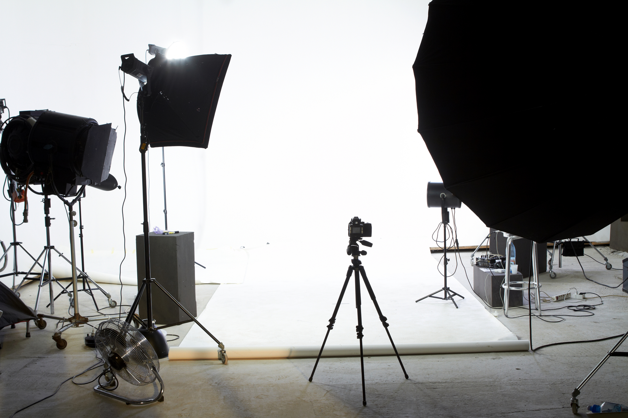 Professional photography studio interior, lights and camera targeting white backdrop.