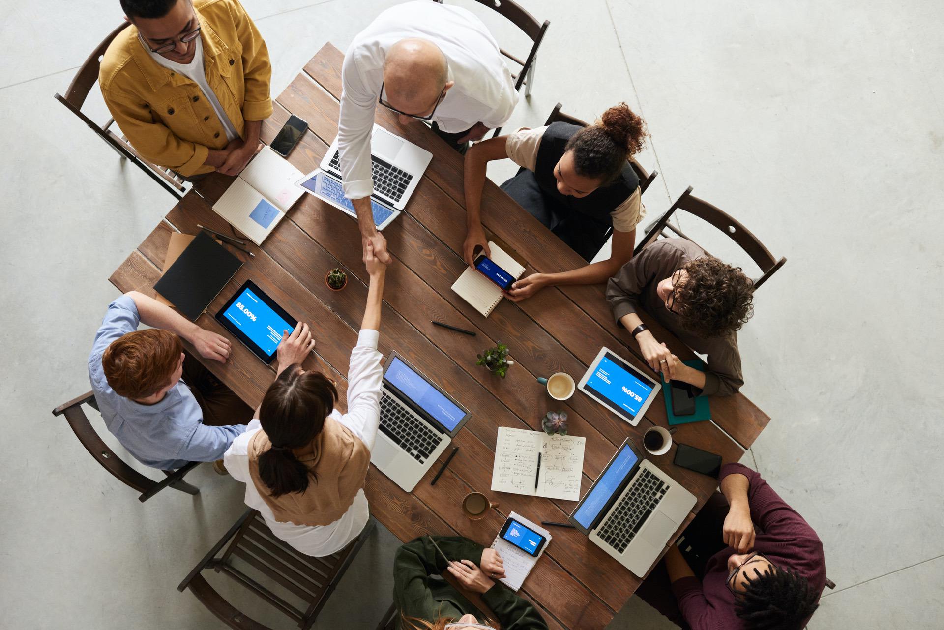 Group of people collaborating around a table with laptops and devices