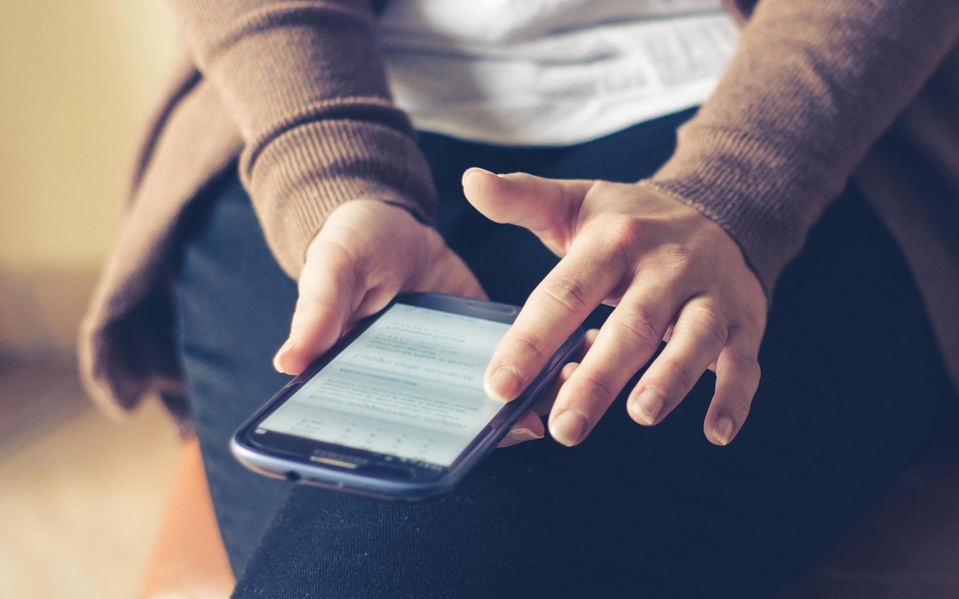 Person using a smartphone while seated, focusing on the screen