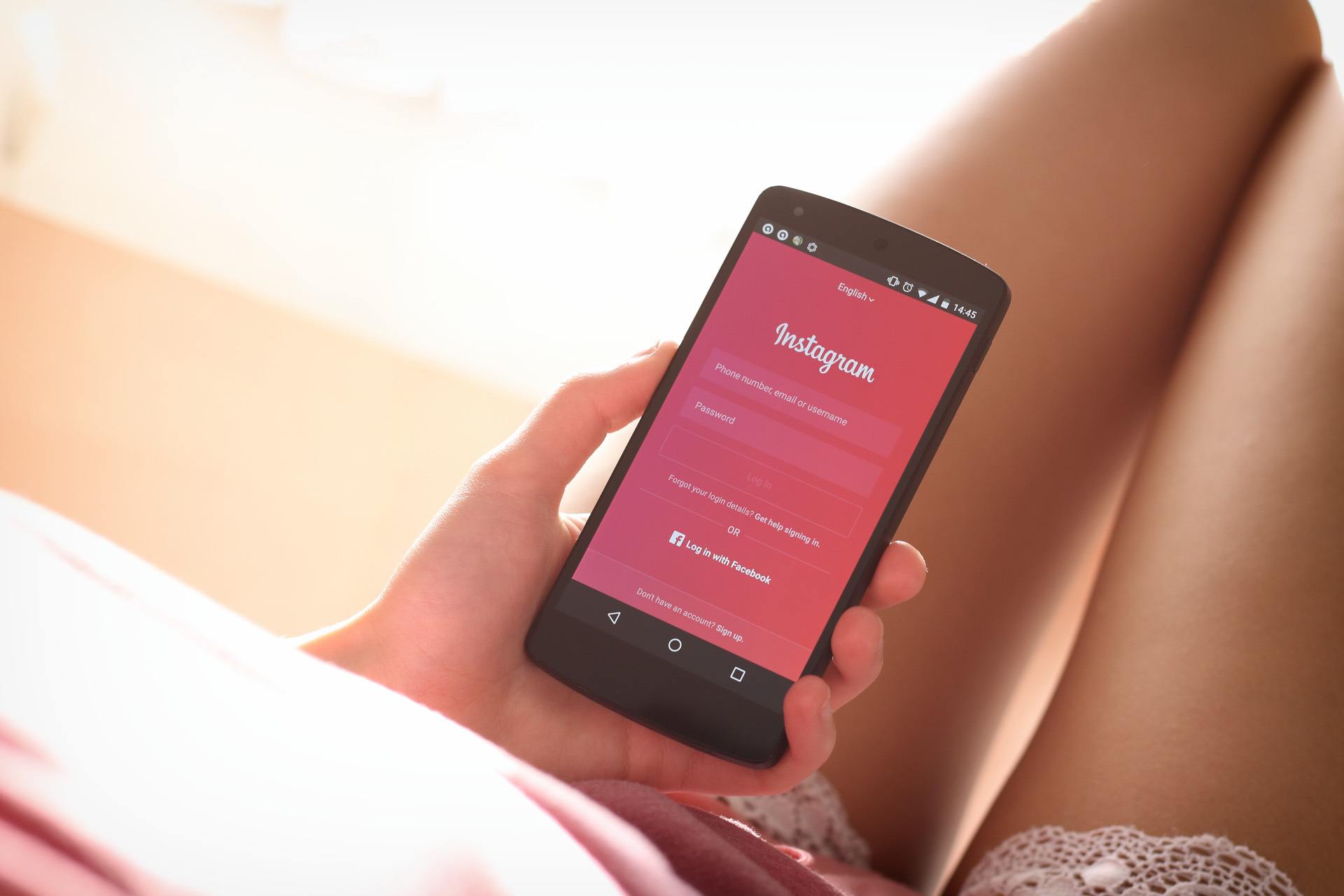 Person holding a smartphone displaying the Instagram login screen