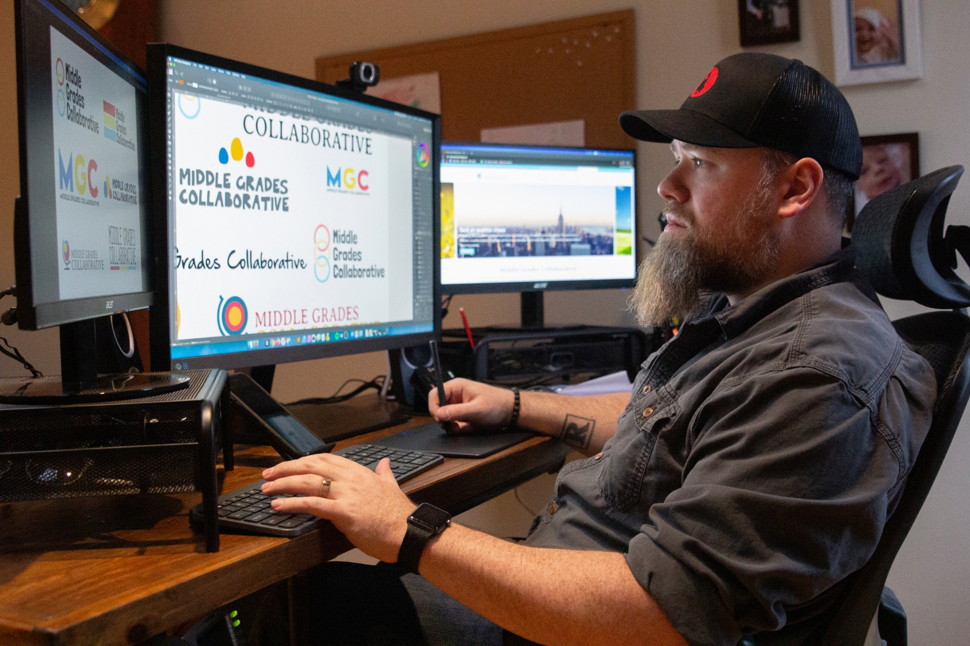 Rob Liberty using digital tablet and stylus to design logos on a multi-screen setup.