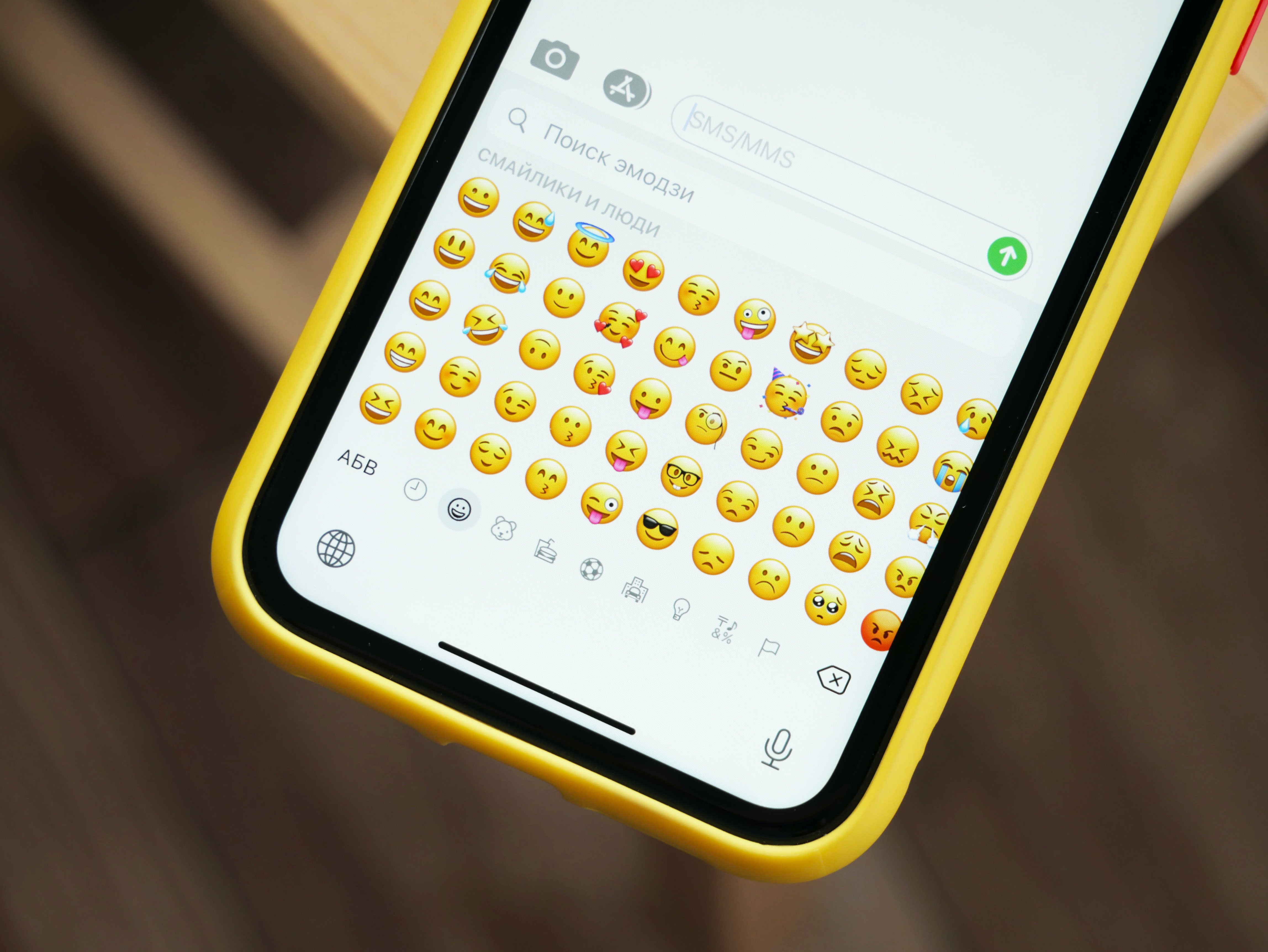 Phone with an emoji keyboard open showing face emojis